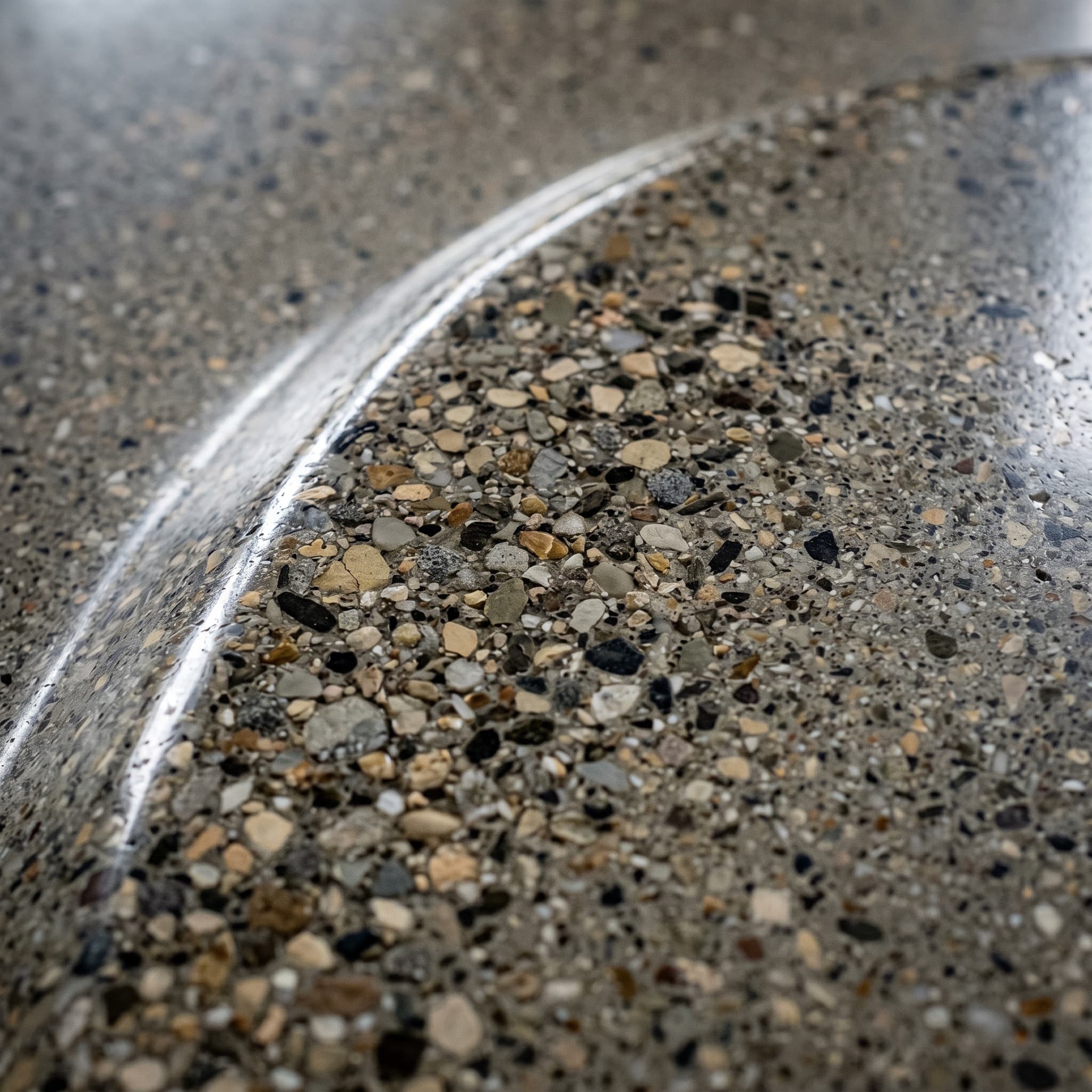 Macro of mirror-polished concrete showing revealed aggregate in cement.