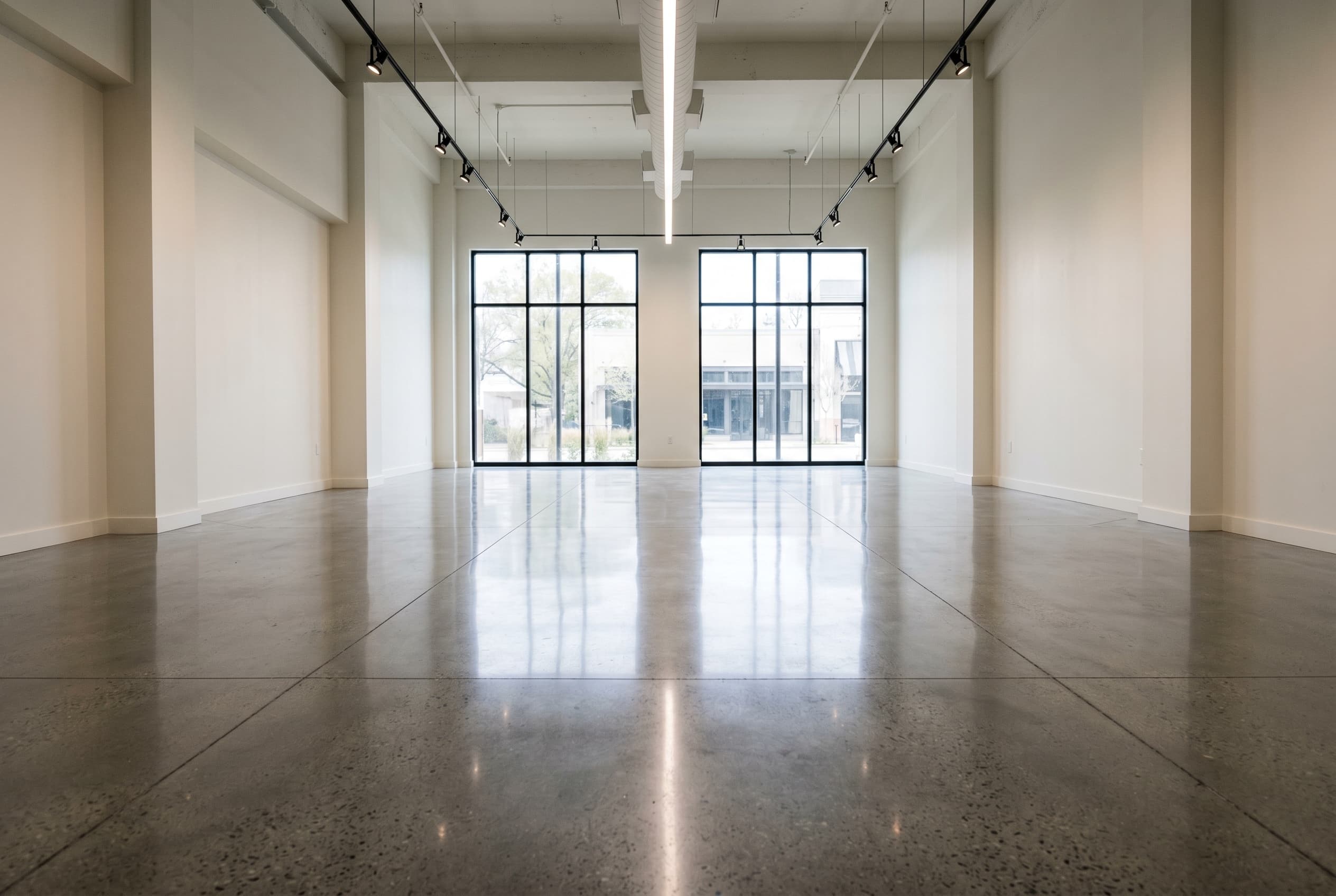 Wide retail showroom with polished concrete floor and track lighting.