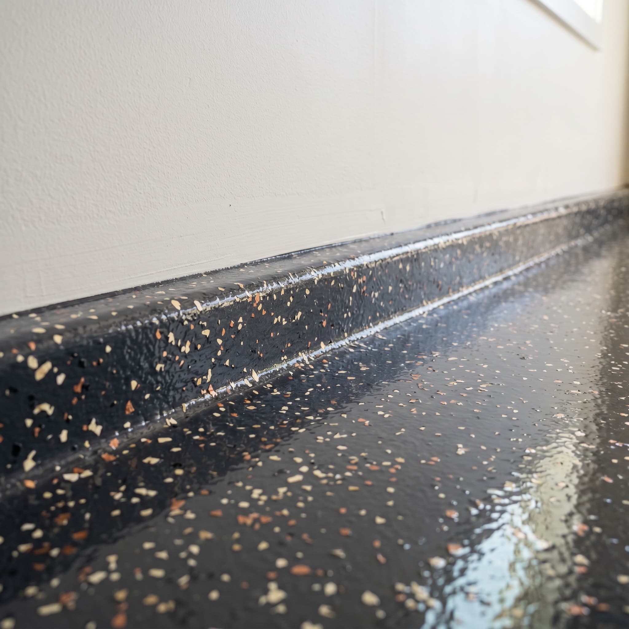 Clean floor-to-wall cove transition on finished Troy garage floor.