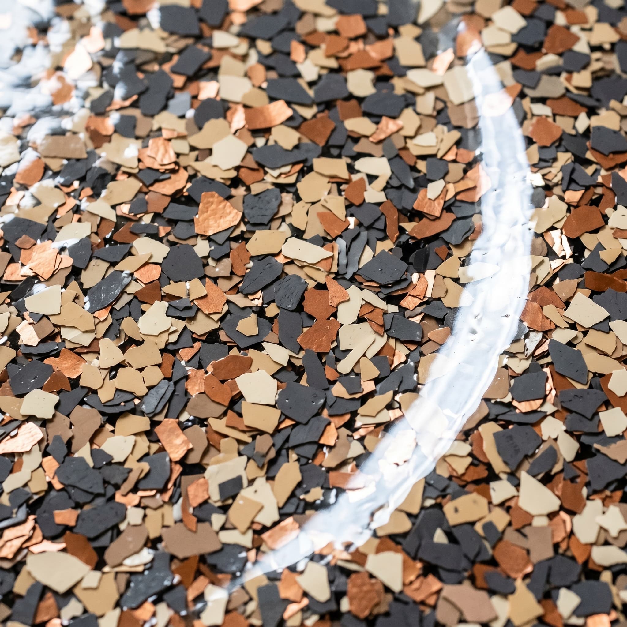 Macro of cured polyaspartic with charcoal, cream, copper flake.